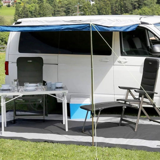 Alfombra Brunner Balmat Premium instalada en zona de camping junto a furgoneta camper y mobiliario exterio