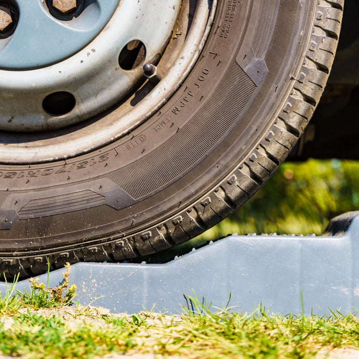 Rueda de vehículo apoyada sobre nivel intermedio de los calzos Fiamma Level Up en superficie irregular