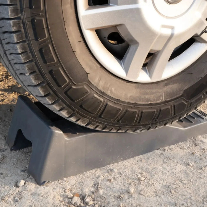 Rueda de vehículo subiendo al primer nivel de los calzos Fiamma Level Up para estabilización en terreno irregular