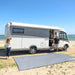 Autocaravana estacionada en la playa con alfombra Fiamma Patio 290 extendida