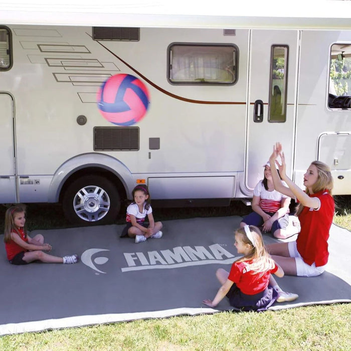 Familia utilizando la alfombra Fiamma Patio-Mat 340 frente a una autocaravana durante una actividad al aire libre