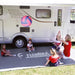 Familia utilizando la alfombra Fiamma Patio-Mat 340 frente a una autocaravana durante una actividad al aire libre
