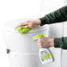 Persona limpiando un inodoro con Thetford Bathroom Cleaner y un paño verde.