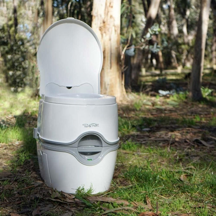 Inodoro portátil Thetford Porta Potti 565E en color blanco utilizado en exterior para camping