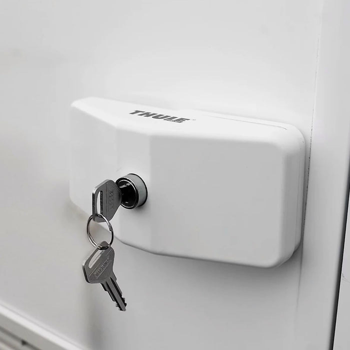 Bloqueador de puerta Thule Door Lock en color blanco instalado en vehículo, con llaves puestas.
