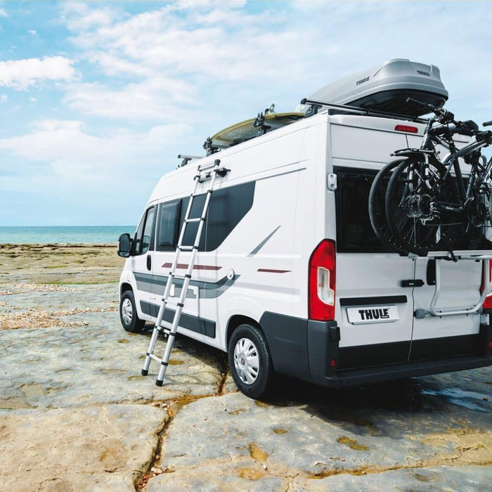Escalera telescópica Thule instalada en una furgoneta camper frente al mar