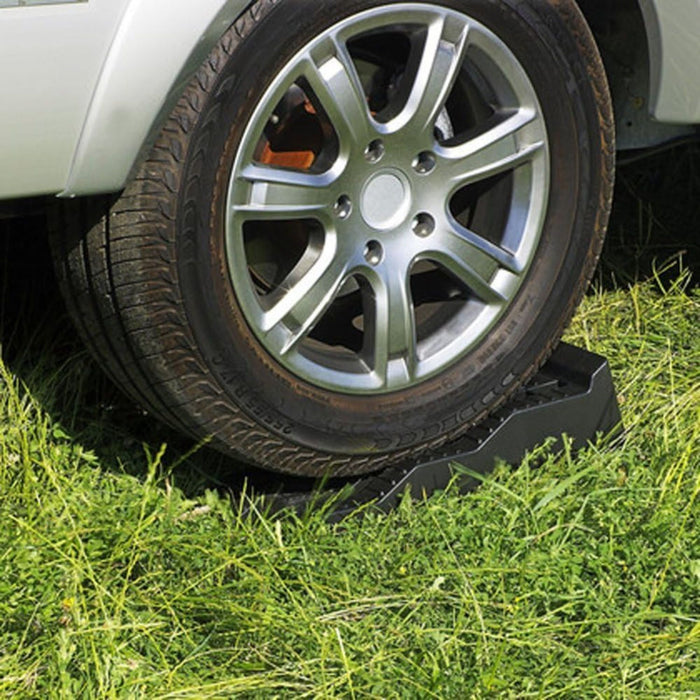 Calzos Thule Levelers colocados bajo la rueda de una autocaravana en terreno de césped