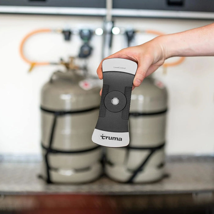 Truma LevelControl sostenido frente a bombonas de gas para indicar nivel digitalmente